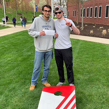 Adam Comuniello 20岁，22岁MBA(左)和Evan Carbognin 20岁赢得了大学的一个坑比赛，这是一个体育事件的巅峰项目的一部分。