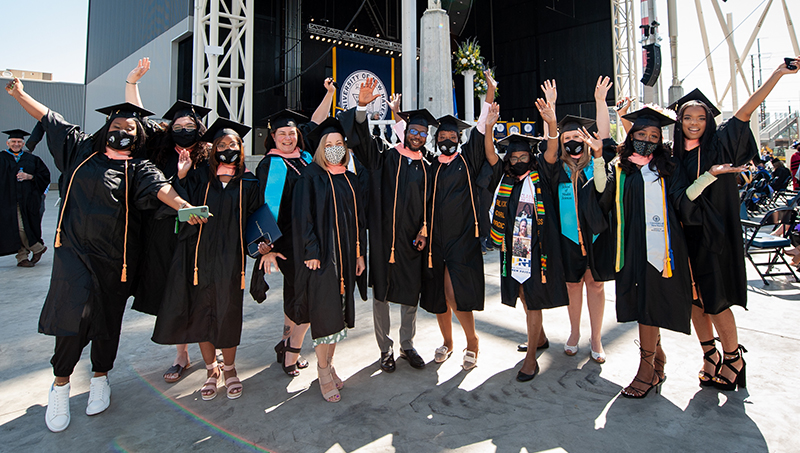 毕业典礼上的学生们，摆姿势拍照，在空中挥舞着他们的手。
