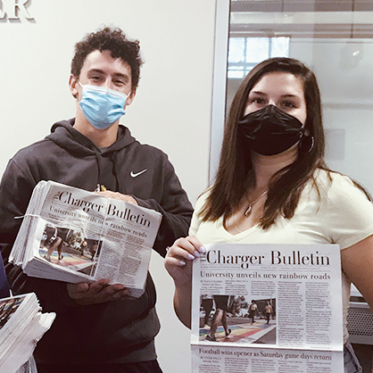 两个学生举着《Charger Bulletin》。